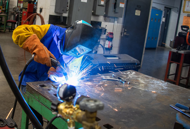 High school student welding at technical college.