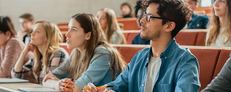 Students seated in a lecture hall, attentively taking notes during a class session