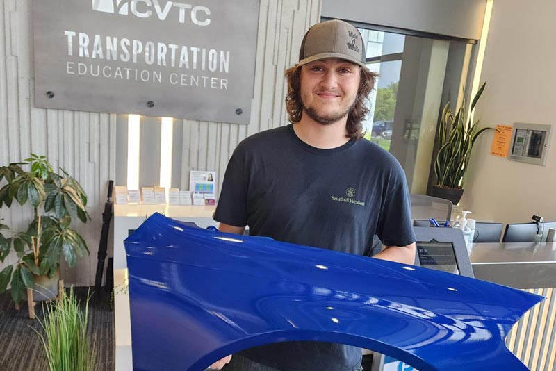 Auto Body Repair student holding car bumper