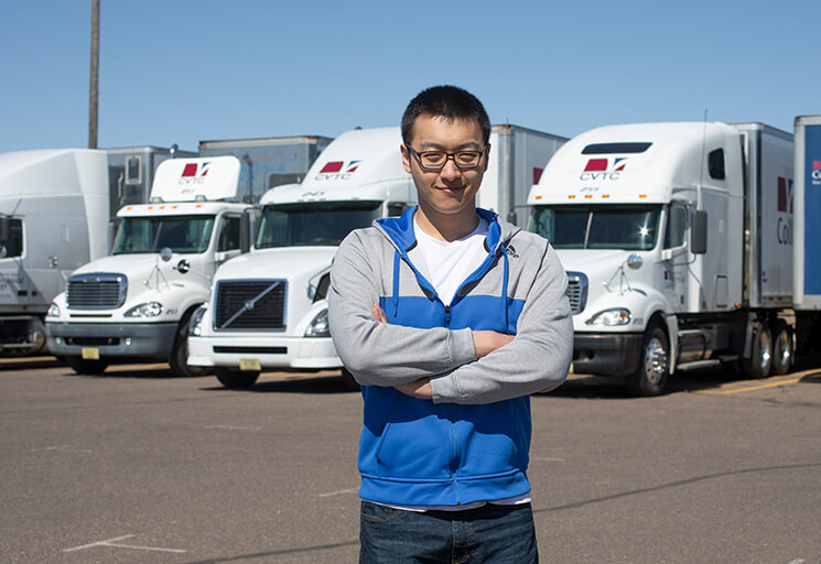 Student standing in front of semi trucks