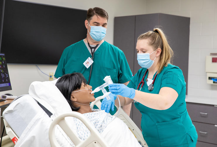 Male and female respiratory therapists working with a healthcare manikin