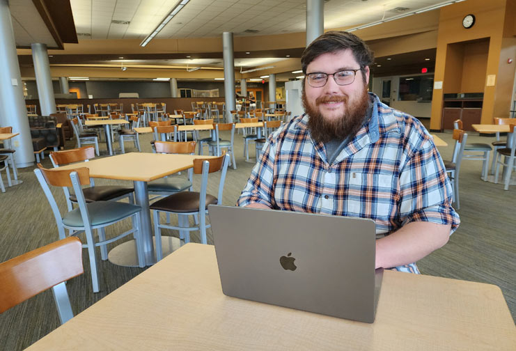 Man with Apple laptop in college commons.