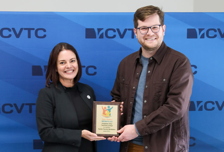 Man and woman holding plaque in front of CVTC step and repeat