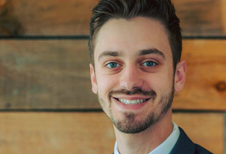 headshot of man in suit with wooden backdrop