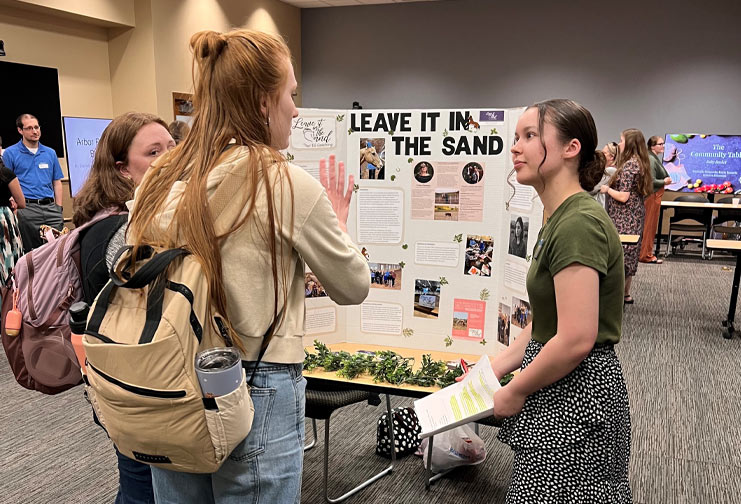 Three females in college presenting on a nursing project