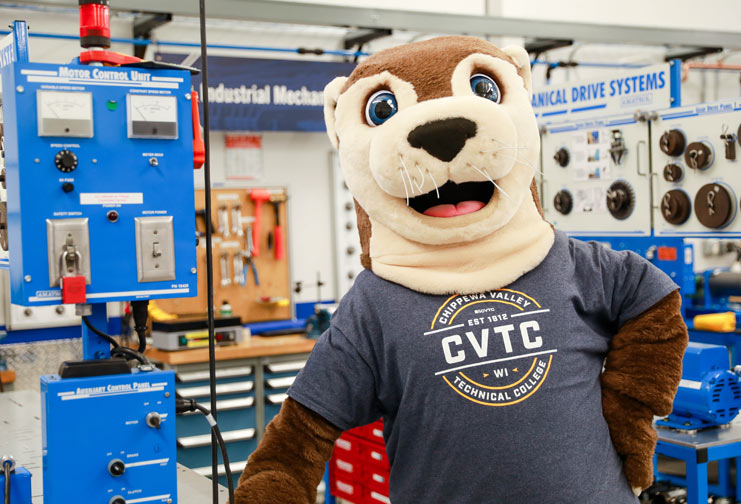 Ollie the CVTC River Otter in a CVTC T-shirt standing in the mechatronics lab