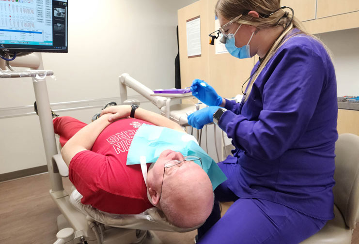 dental student at college giving man a dental cleaning