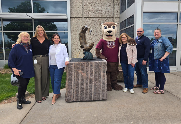People from the Eau Claire Sculpture Tour and Chippewa Valley Technical College standing near the new river otter sculpture on the sculpture tour.