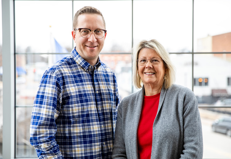 Tyler Mason, communications coordinator for the City of River Falls, and Karen Bergstrom, human resources director for the City of River Falls, stand inside the city building overlooking the city of River Falls.