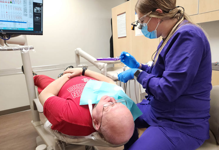 Man in dental chair being seen by CVTC dental hygiene student.